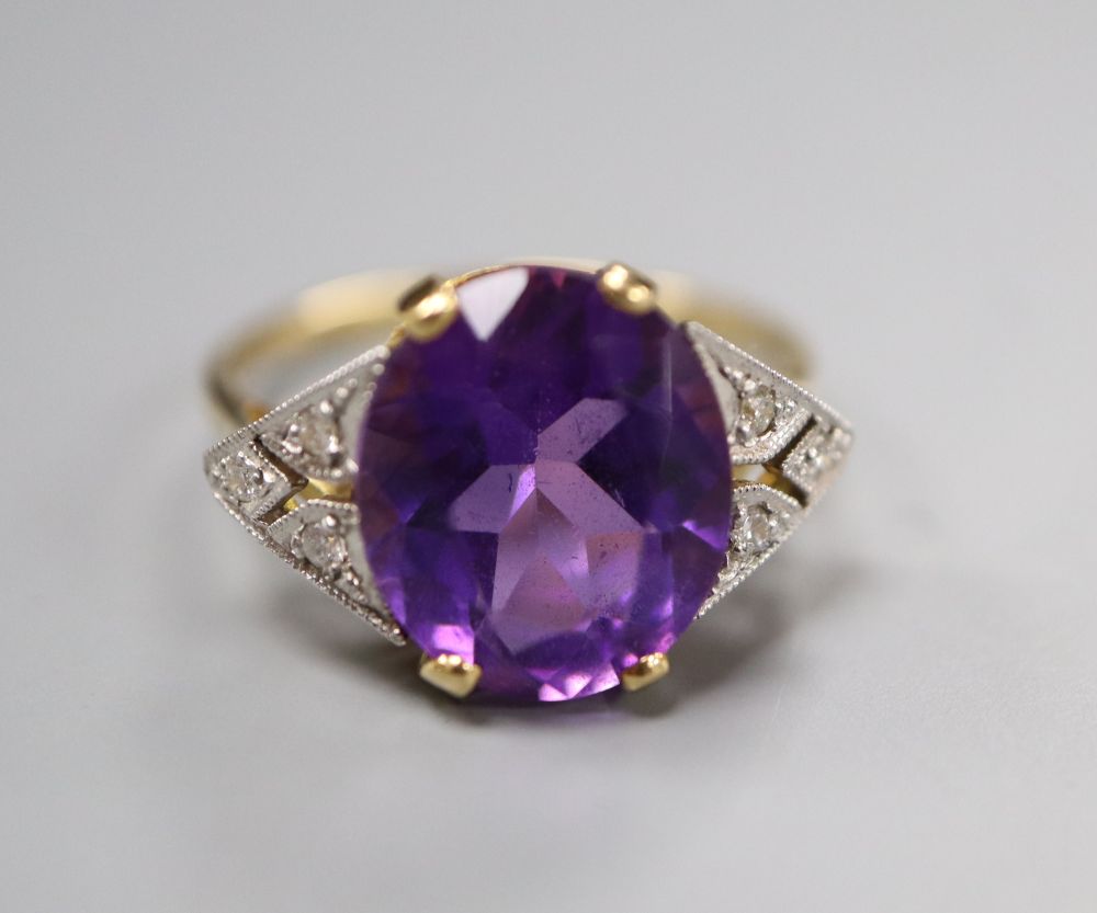 An Art Deco style yellow metal, amethyst and diamond seven-stone ring, the oval amethyst claw-set, size N, gross 3.7 grams.